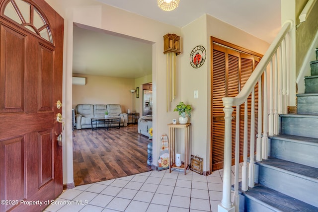 foyer with stairs, a wall unit AC, and light tile patterned flooring