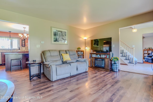 living room featuring a fireplace, wood finished floors, a chandelier, and stairway