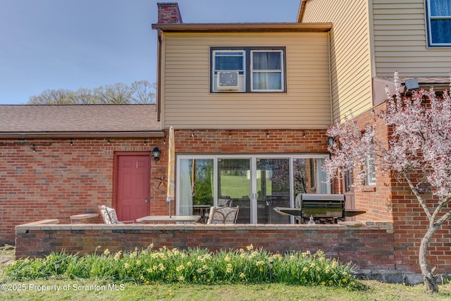 back of house featuring a chimney and brick siding