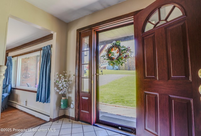 foyer entrance with baseboards, a baseboard heating unit, light tile patterned flooring, and a wealth of natural light