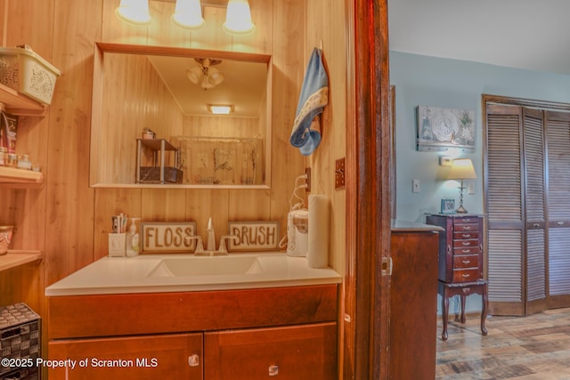 bathroom with wood walls, a sink, and wood finished floors