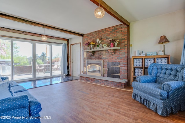 living area with a fireplace, beamed ceiling, and wood finished floors