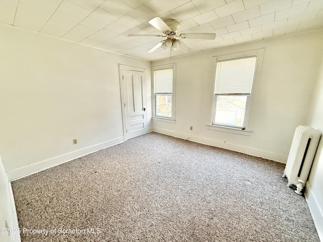 unfurnished bedroom featuring baseboards, carpet floors, a ceiling fan, and radiator