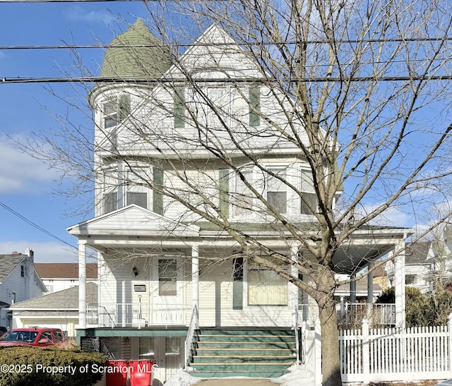 victorian-style house featuring a porch and fence