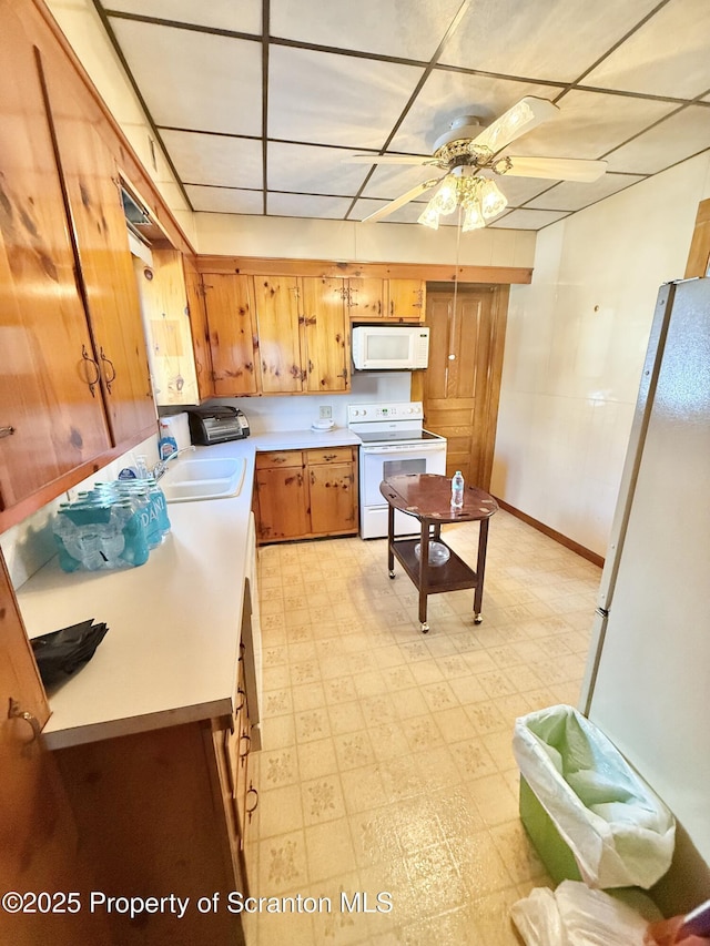 kitchen featuring ceiling fan, white appliances, light countertops, brown cabinets, and light floors