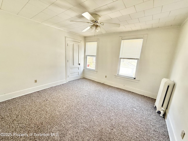 empty room with radiator, carpet, baseboards, and a ceiling fan