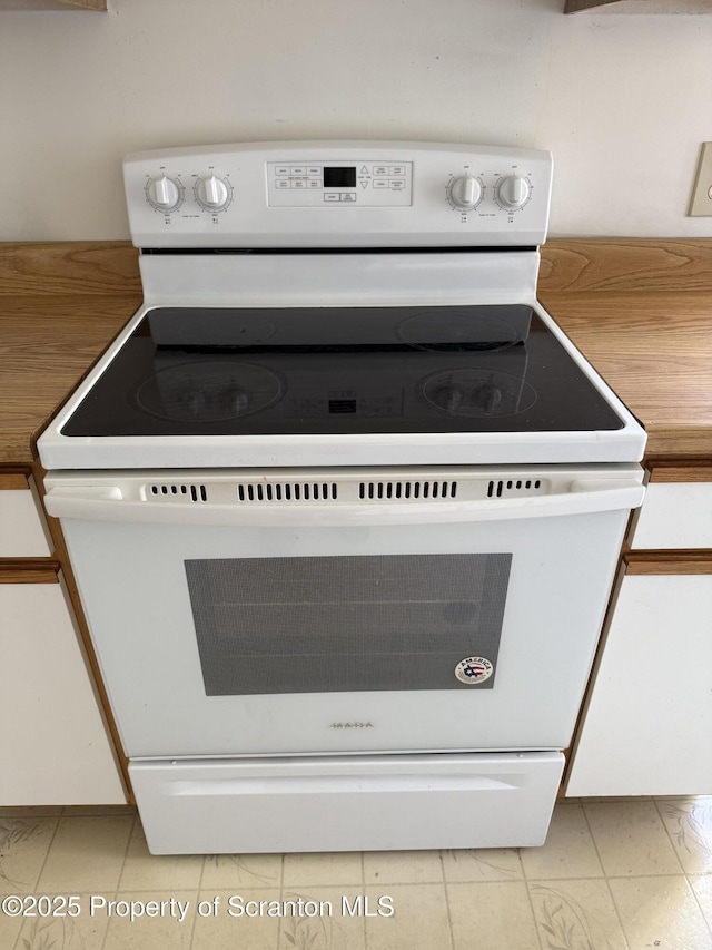 room details featuring light countertops, white cabinetry, and white range with electric cooktop