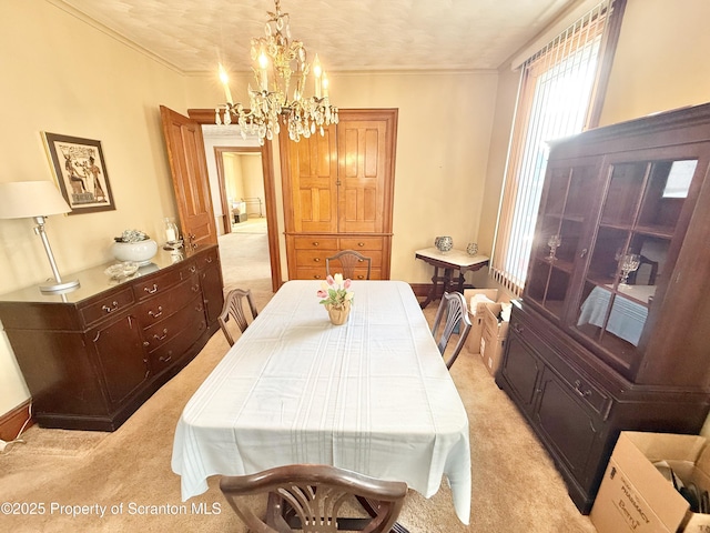 dining room with a notable chandelier, crown molding, and light colored carpet