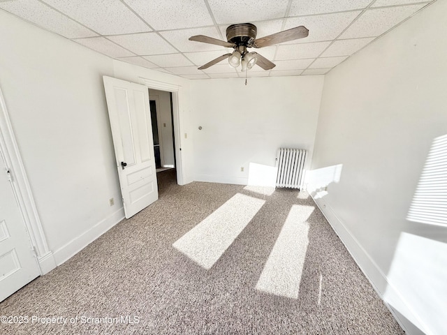 carpeted spare room featuring ceiling fan, a drop ceiling, and baseboards