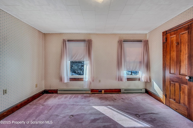 carpeted spare room with a baseboard radiator and a wealth of natural light