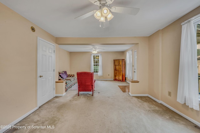 living area with baseboards, ceiling fan, and carpet flooring