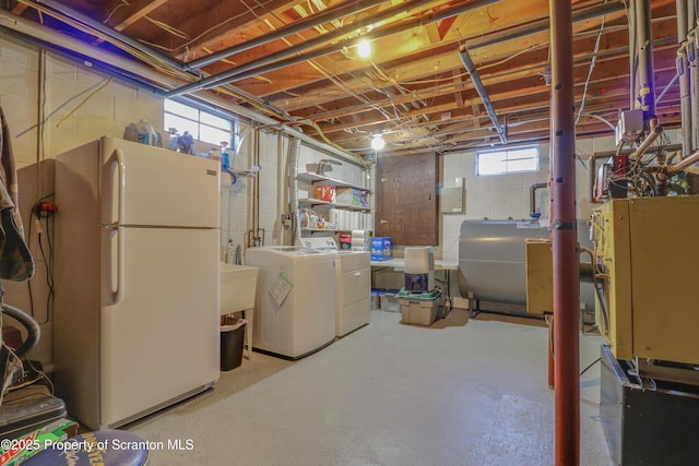 below grade area featuring washer and clothes dryer, freestanding refrigerator, and heating fuel