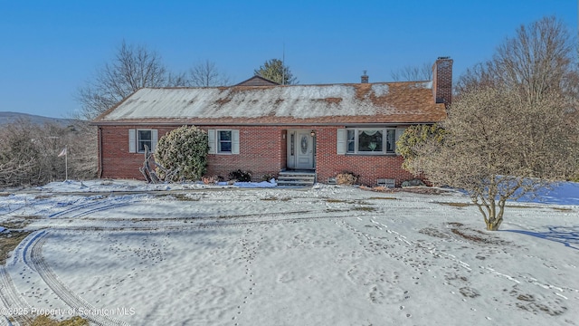 view of front of property with crawl space, a chimney, and brick siding