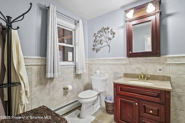 bathroom featuring tile walls, toilet, a baseboard heating unit, wainscoting, and vanity