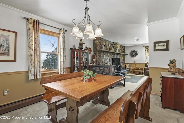 dining room with a baseboard heating unit, a stone fireplace, ornamental molding, and light colored carpet