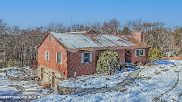 view of front of home featuring an attached garage, a chimney, and brick siding