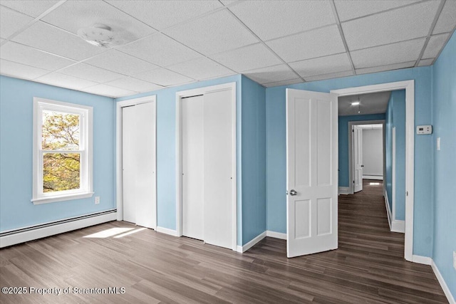 316 Sibley Ave, Old Forge, PA 18518 - unfurnished bedroom with wood finished floors, a baseboard heating unit, baseboards, a drop ceiling, and multiple closets
