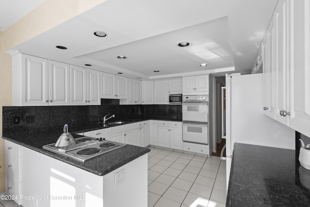 kitchen featuring a raised ceiling, double oven, white cabinets, gas cooktop, and light tile patterned flooring