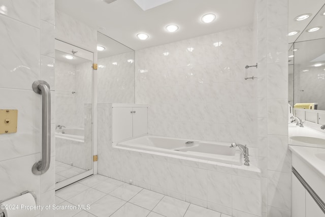 bathroom featuring tile walls, vanity, tiled tub, and tile patterned floors