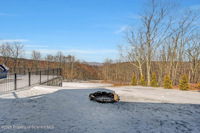 view of yard featuring a wooded view and fence