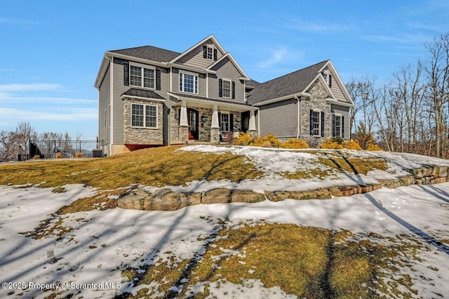 view of front of house featuring cooling unit, stone siding, covered porch, and fence