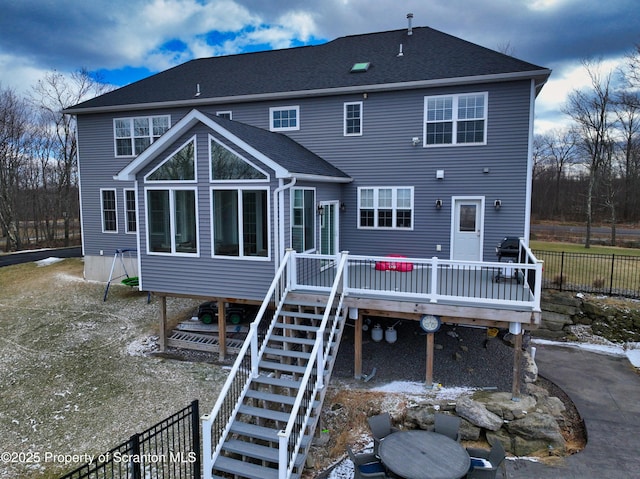 back of house with a deck, roof with shingles, fence, and stairway