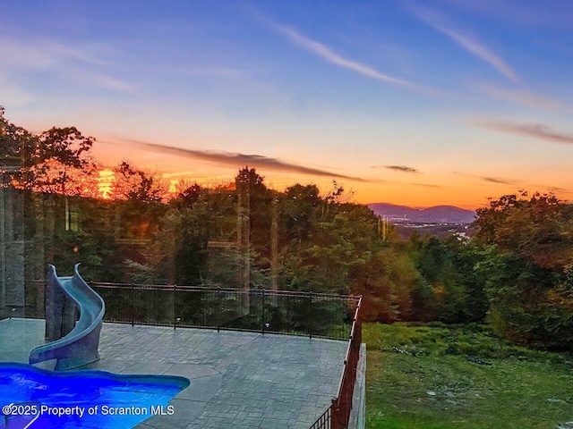 pool at dusk featuring a patio area