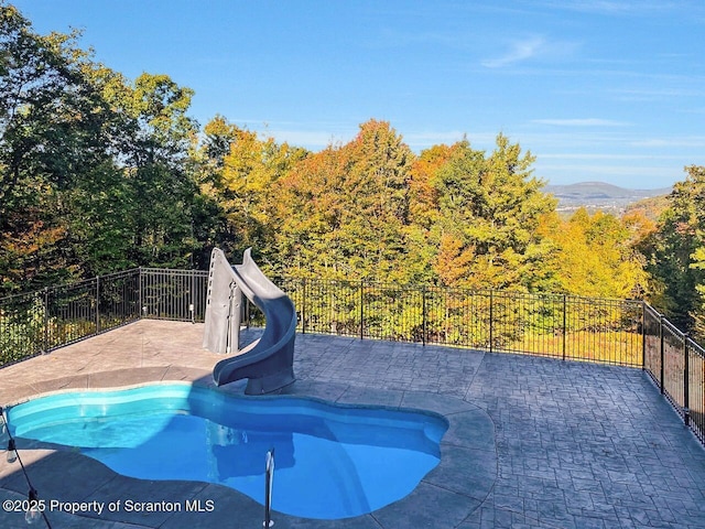 view of pool featuring a water slide, a patio area, fence, and a fenced in pool