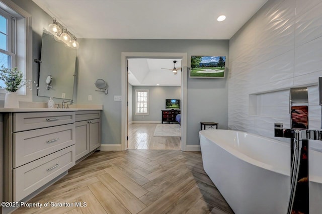 full bathroom featuring a freestanding tub, recessed lighting, baseboards, and vanity