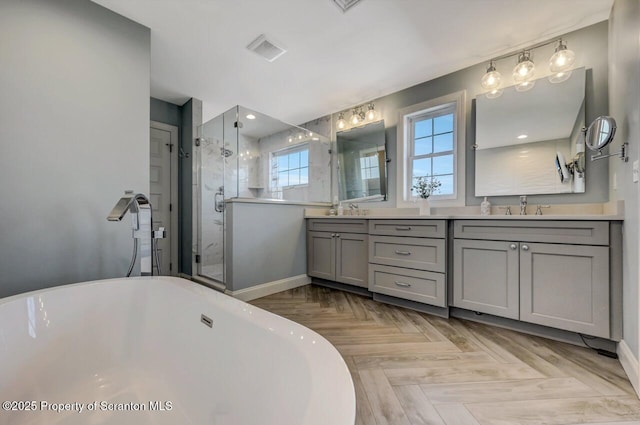 bathroom with a sink, double vanity, a freestanding tub, and a shower stall