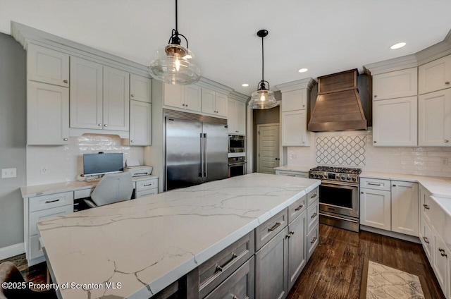 kitchen with custom range hood, dark wood-type flooring, built in appliances, light stone countertops, and backsplash