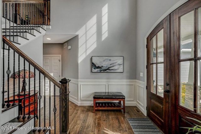 entryway featuring stairs, wainscoting, wood finished floors, and a decorative wall