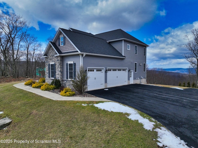 view of home's exterior with driveway, a garage, stone siding, roof with shingles, and a yard