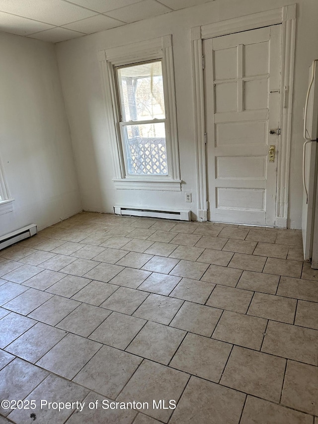 spare room featuring light tile patterned floors, a baseboard heating unit, and a paneled ceiling