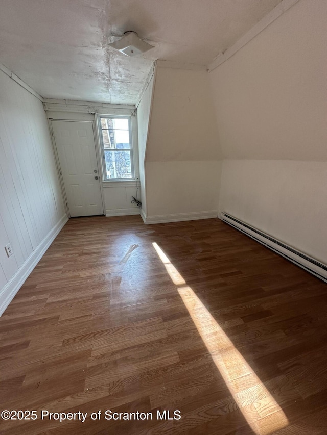 additional living space featuring a baseboard heating unit, baseboards, and wood finished floors