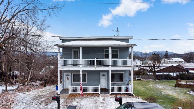 front of property with a mountain view, a balcony, and a lawn