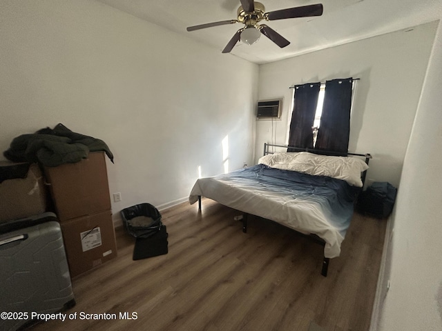 bedroom with ceiling fan, an AC wall unit, and wood-type flooring