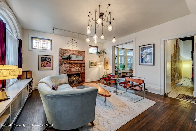 living room with dark hardwood / wood-style floors, a healthy amount of sunlight, a fireplace, and a chandelier