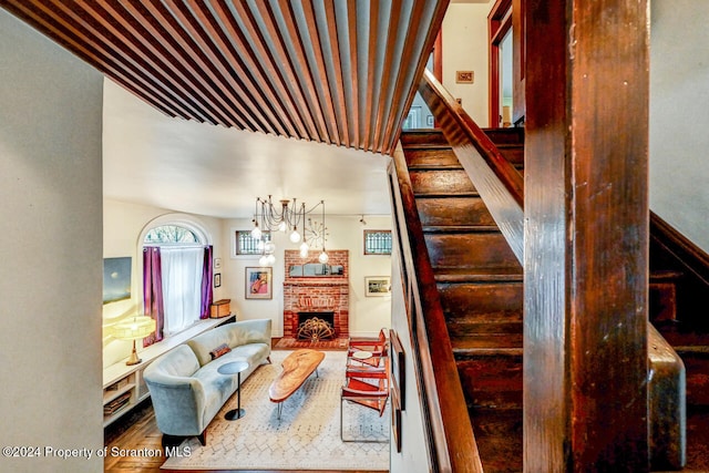 stairway with a fireplace, hardwood / wood-style floors, and an inviting chandelier