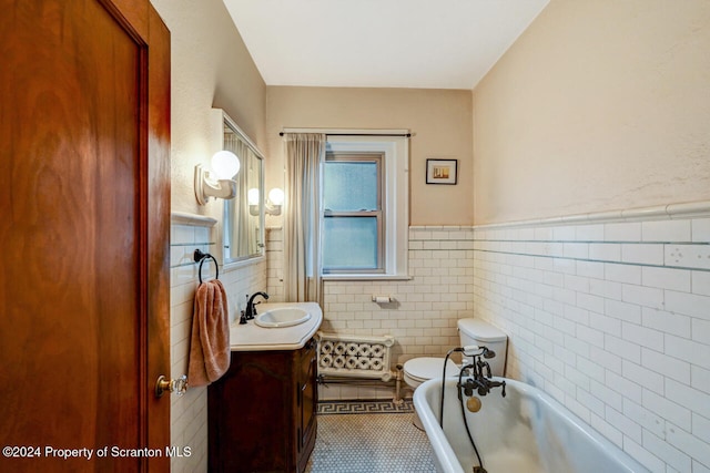 bathroom featuring vanity, tile patterned floors, a washtub, toilet, and tile walls