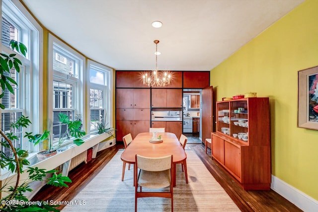 dining room with plenty of natural light, dark wood-type flooring, and a chandelier