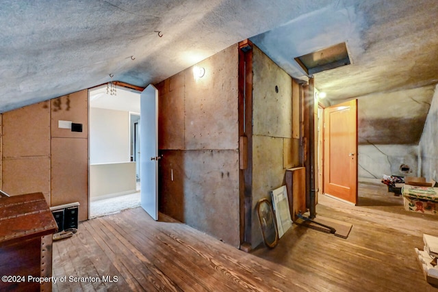 corridor with hardwood / wood-style flooring and vaulted ceiling