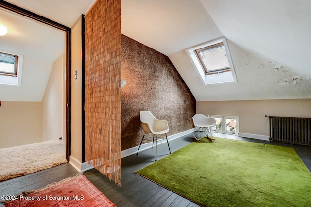 bonus room with lofted ceiling with skylight, dark hardwood / wood-style flooring, and radiator heating unit