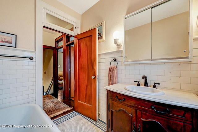 bathroom featuring a washtub, vanity, and tile walls