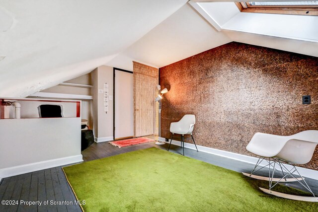 additional living space featuring dark hardwood / wood-style floors and lofted ceiling with skylight