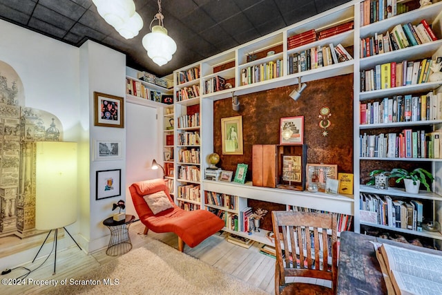 living area with built in shelves, a drop ceiling, and wood-type flooring