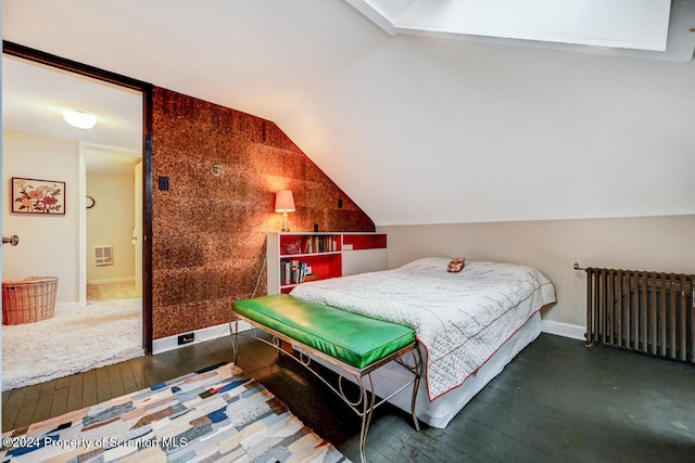 bedroom with radiator, dark hardwood / wood-style flooring, and lofted ceiling