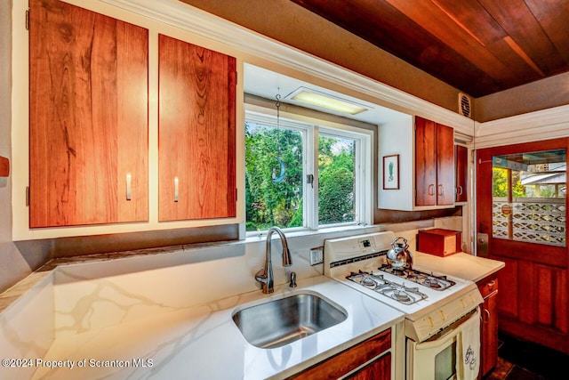 kitchen featuring white gas range oven, wooden ceiling, and sink