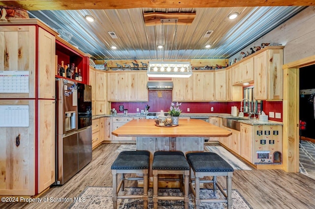 kitchen featuring appliances with stainless steel finishes, sink, light brown cabinetry, and range hood