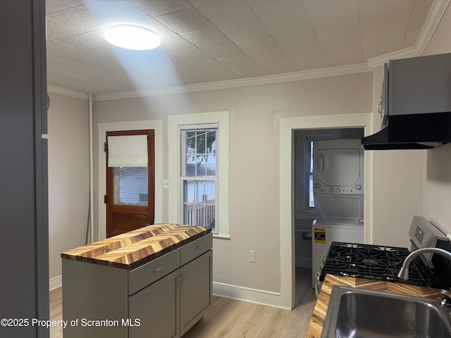 kitchen featuring sink, stacked washer / drying machine, ornamental molding, and gray cabinetry